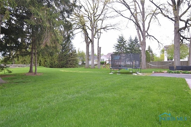view of yard with a trampoline and fence