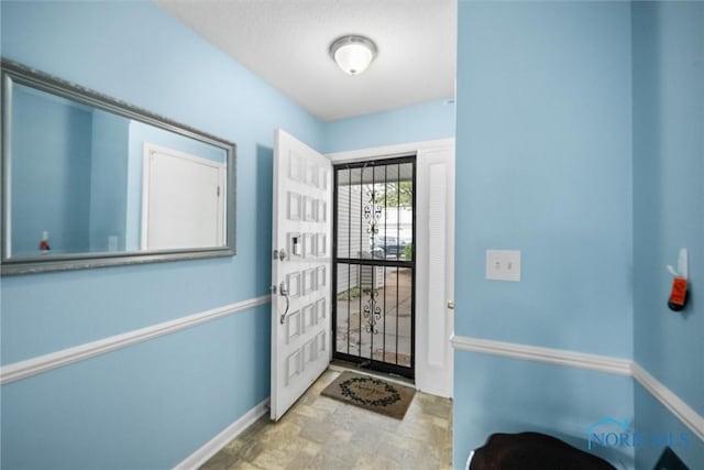 foyer featuring baseboards and stone finish floor