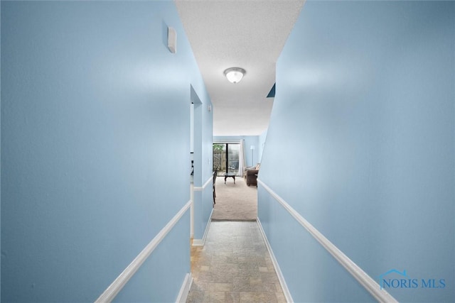 hall with baseboards and stone finish flooring