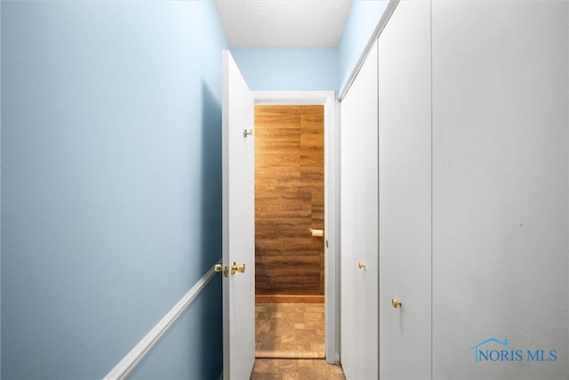 corridor with a textured ceiling and stone finish floor