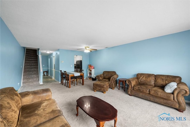 carpeted living room featuring stairway and a ceiling fan