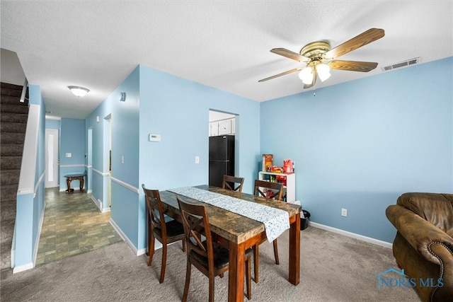 dining space featuring ceiling fan, visible vents, stairway, baseboards, and carpet