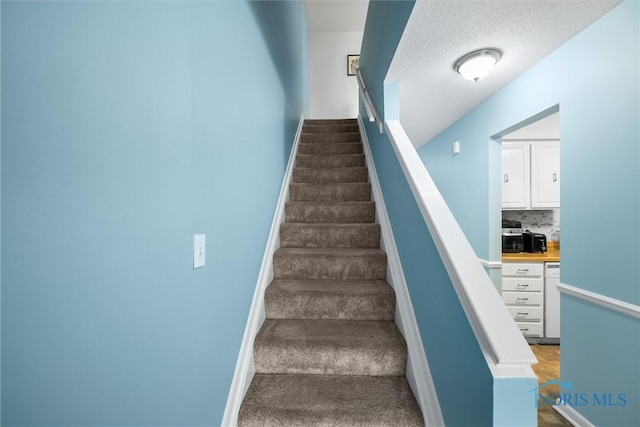 staircase with baseboards and carpet flooring