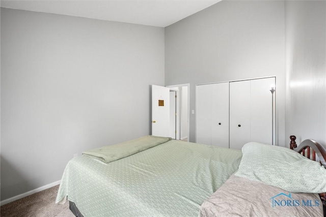 carpeted bedroom featuring baseboards, a closet, and a towering ceiling
