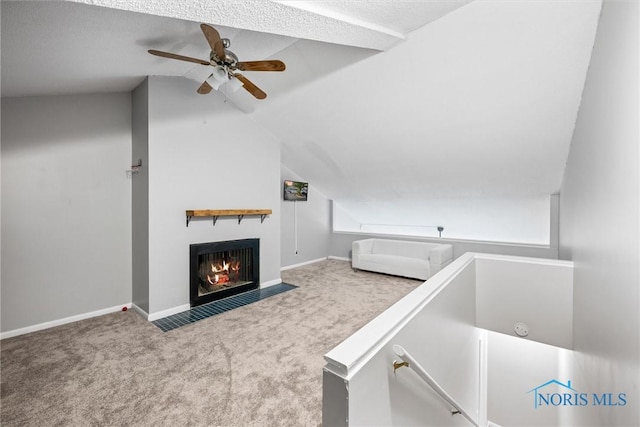 unfurnished bedroom featuring baseboards, a fireplace with flush hearth, carpet, and vaulted ceiling