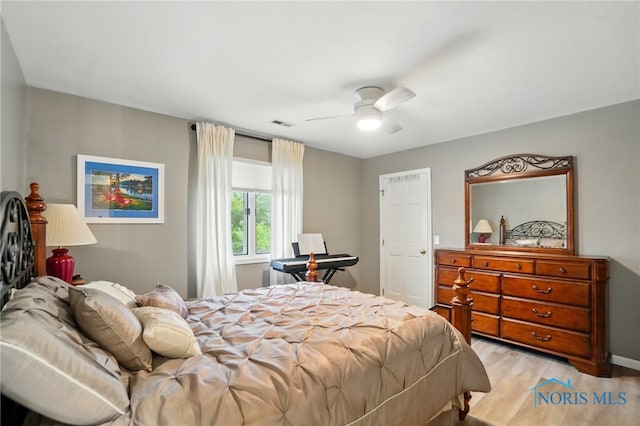 bedroom featuring a ceiling fan, visible vents, and light wood finished floors