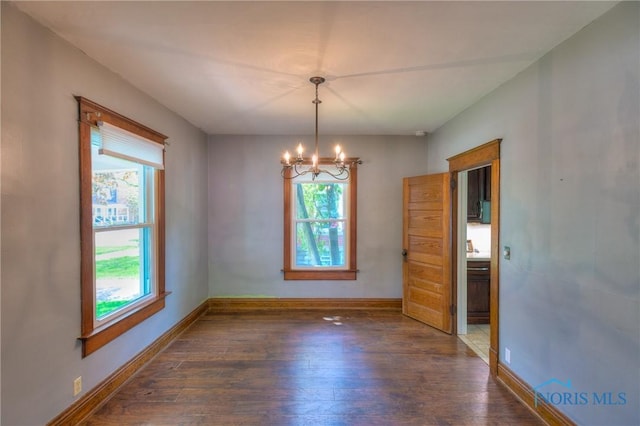 229 E Harrison St, Maumee, OH 43537 - empty room featuring baseboards, hardwood / wood-style floors, a healthy amount of sunlight, and an inviting chandelier