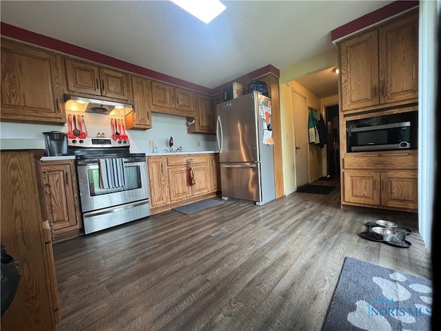107 Oak Park Dr, Hicksville, OH 43526 - kitchen with stainless steel appliances, under cabinet range hood, dark wood-type flooring, light countertops, and brown cabinets