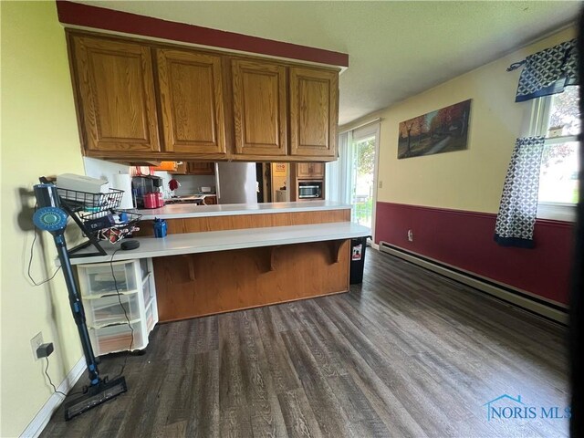 107 Oak Park Dr, Hicksville, OH 43526 - kitchen featuring baseboard heating, dark wood-style floors, brown cabinetry, and a peninsula