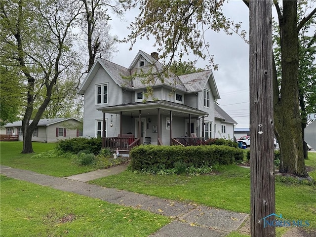 view of front of house featuring a chimney, a front yard, and a porch