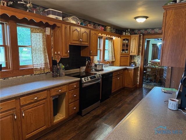 kitchen featuring black dishwasher, dark wood finished floors, a sink, electric stove, and brown cabinets