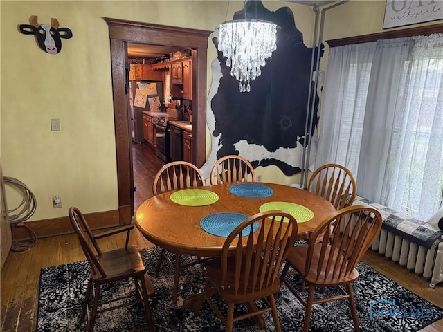 dining space with baseboards, a chandelier, and wood finished floors