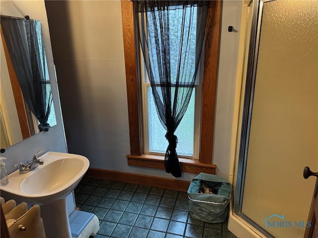 full bath featuring baseboards, tile patterned flooring, a stall shower, and a sink