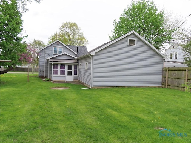 rear view of property with a yard and fence