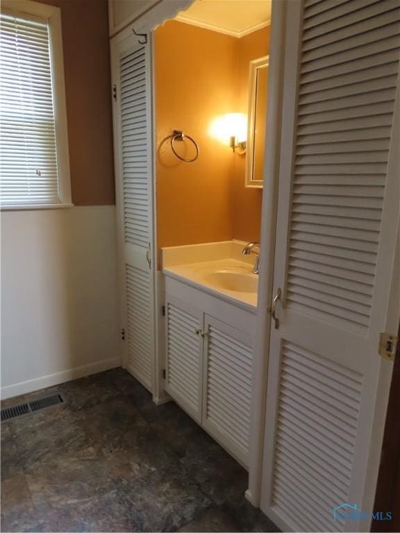 bathroom with a closet, visible vents, baseboards, and vanity