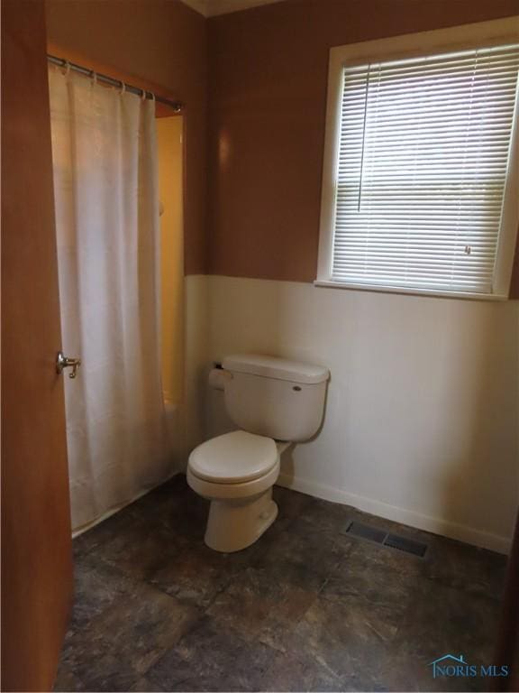 full bathroom with toilet, a shower with shower curtain, and visible vents