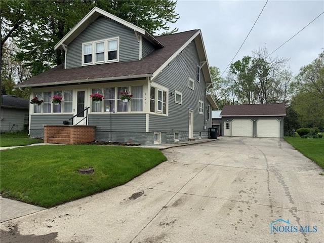 view of front of house featuring a garage, a front lawn, an outbuilding, and a shingled roof