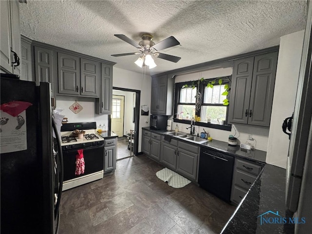 kitchen featuring gray cabinetry, ceiling fan, a sink, black appliances, and dark countertops