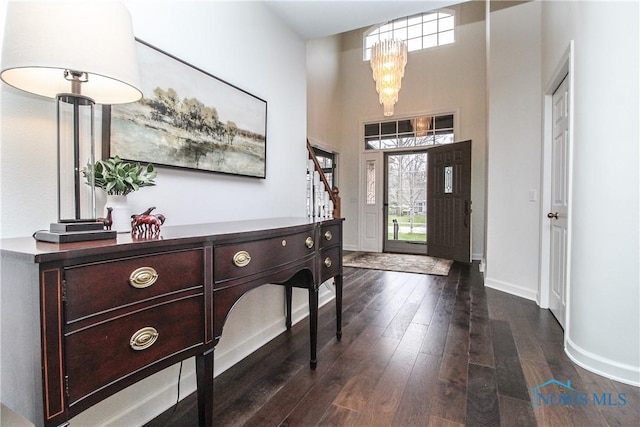 foyer entrance with baseboards, a chandelier, and dark wood-type flooring