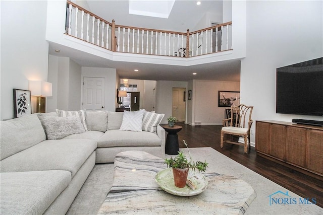 living room with recessed lighting, baseboards, a high ceiling, wood finished floors, and a skylight