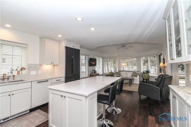 kitchen with high quality fridge, a sink, open floor plan, dark wood-type flooring, and vaulted ceiling