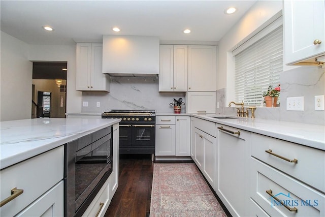 kitchen featuring range with two ovens, black microwave, white cabinetry, and a sink