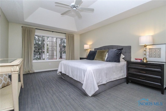bedroom featuring carpet flooring, baseboards, a raised ceiling, and ceiling fan