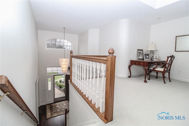 foyer with carpet floors, baseboards, and an inviting chandelier