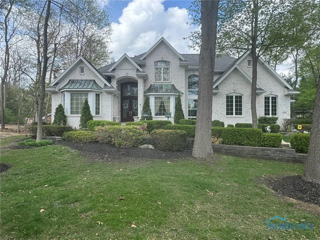 french provincial home featuring brick siding and a front yard