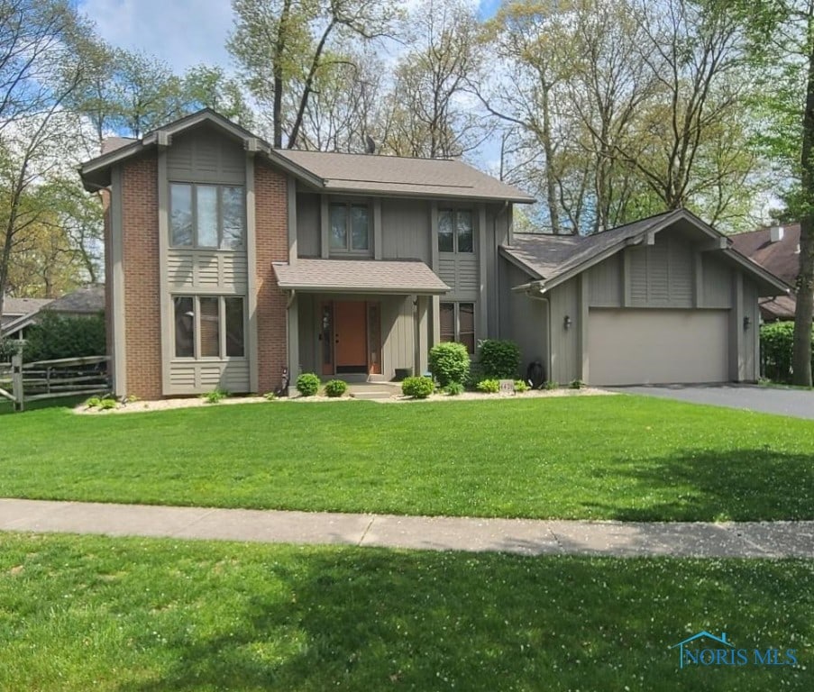 traditional-style home with a garage, fence, aphalt driveway, a front lawn, and board and batten siding