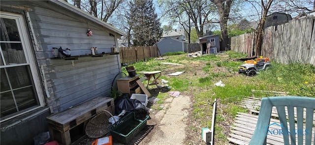 view of yard featuring an outbuilding, a fenced backyard, and a storage unit