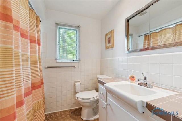 3448 Corey Rd, Toledo, OH 43615 - full bathroom with tile walls, toilet, vanity, tile patterned floors, and a wainscoted wall
