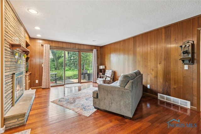 3448 Corey Rd, Toledo, OH 43615 - living area with a stone fireplace, a textured ceiling, wood walls, wood-type flooring, and recessed lighting