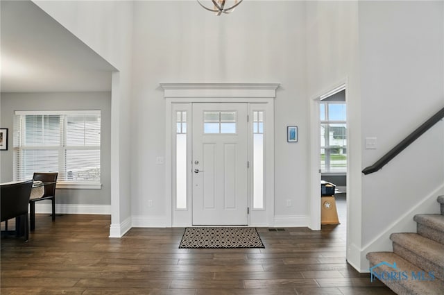 entryway featuring a high ceiling, stairs, baseboards, and dark wood-style flooring