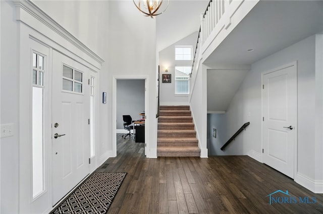 foyer entrance featuring dark wood finished floors, stairway, baseboards, and high vaulted ceiling