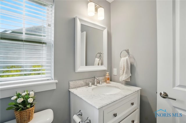 half bath featuring vanity and toilet