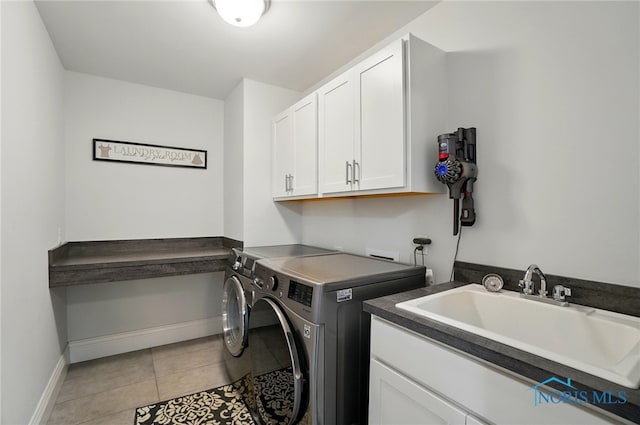 clothes washing area with cabinet space, washing machine and dryer, baseboards, and light tile patterned floors