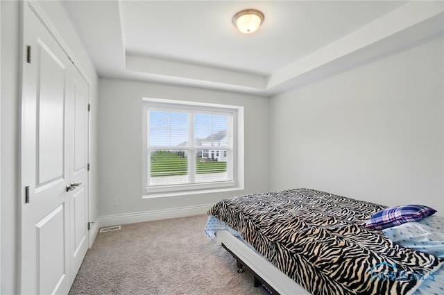 bedroom featuring carpet flooring, a tray ceiling, and baseboards