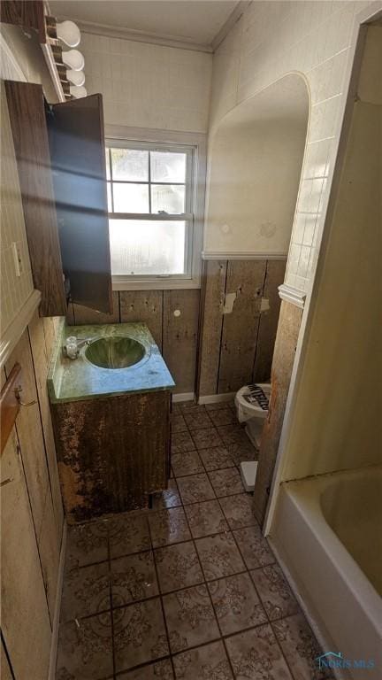 full bath with toilet, ornamental molding, vanity, and a tub to relax in