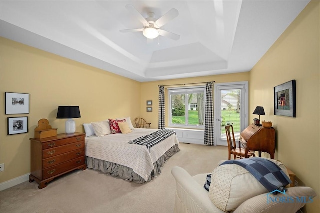 bedroom with a ceiling fan, a raised ceiling, and light colored carpet