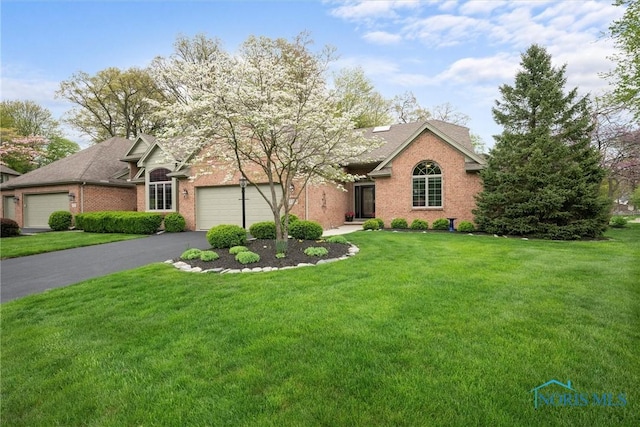 view of front of home featuring a front lawn, brick siding, driveway, and a garage