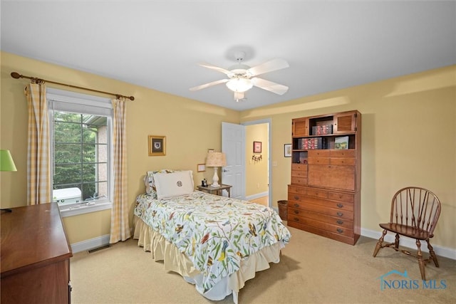 bedroom featuring light colored carpet, baseboards, and a ceiling fan