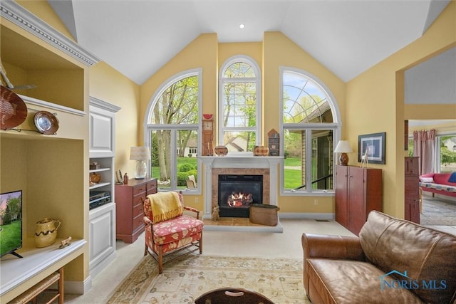 living area with light colored carpet, a healthy amount of sunlight, and a glass covered fireplace