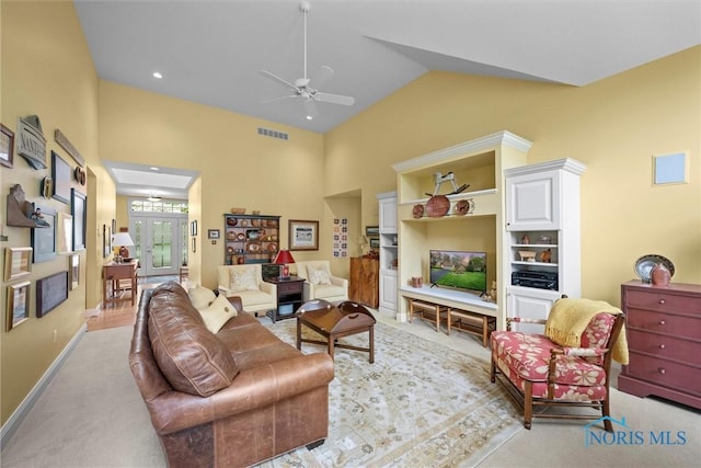 living area featuring baseboards, ceiling fan, visible vents, high vaulted ceiling, and light colored carpet