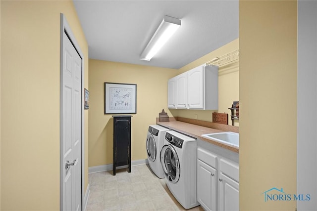clothes washing area with washer and clothes dryer, a sink, cabinet space, and baseboards