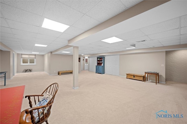basement featuring a paneled ceiling, baseboards, visible vents, and carpet floors
