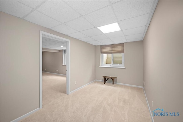 unfurnished room featuring light carpet, baseboards, and a drop ceiling