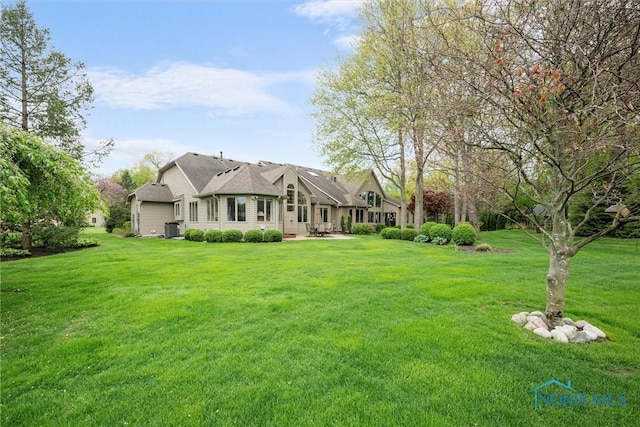 exterior space featuring central air condition unit, a patio, an attached garage, and a lawn