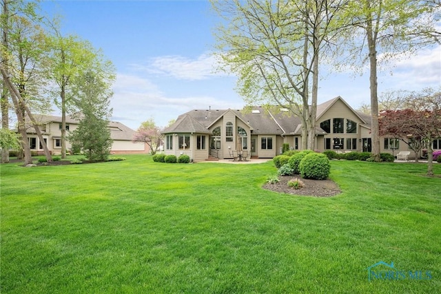 rear view of property featuring a yard and a patio area