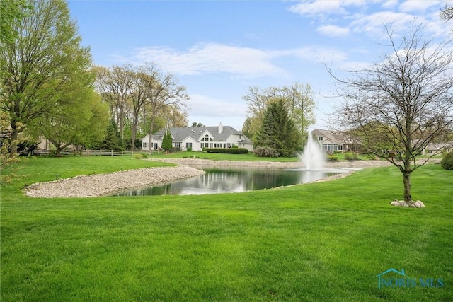 view of home's community featuring a yard, a water view, and fence
